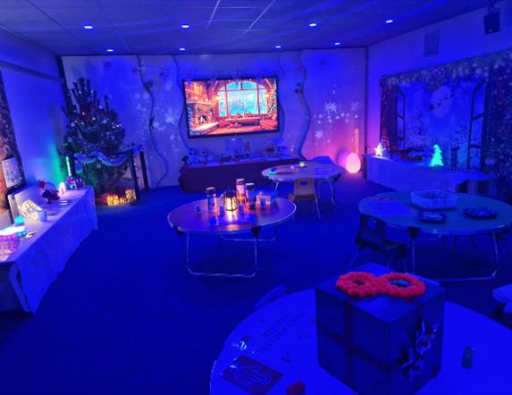 A softly lit sensory room at Marble Arch Caves decorated for Christmas, glowing with calming blue lights. Visitors explore gentle interactive sensory