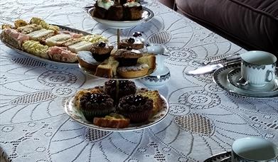 A table laid with plates of cakes and sandwiches