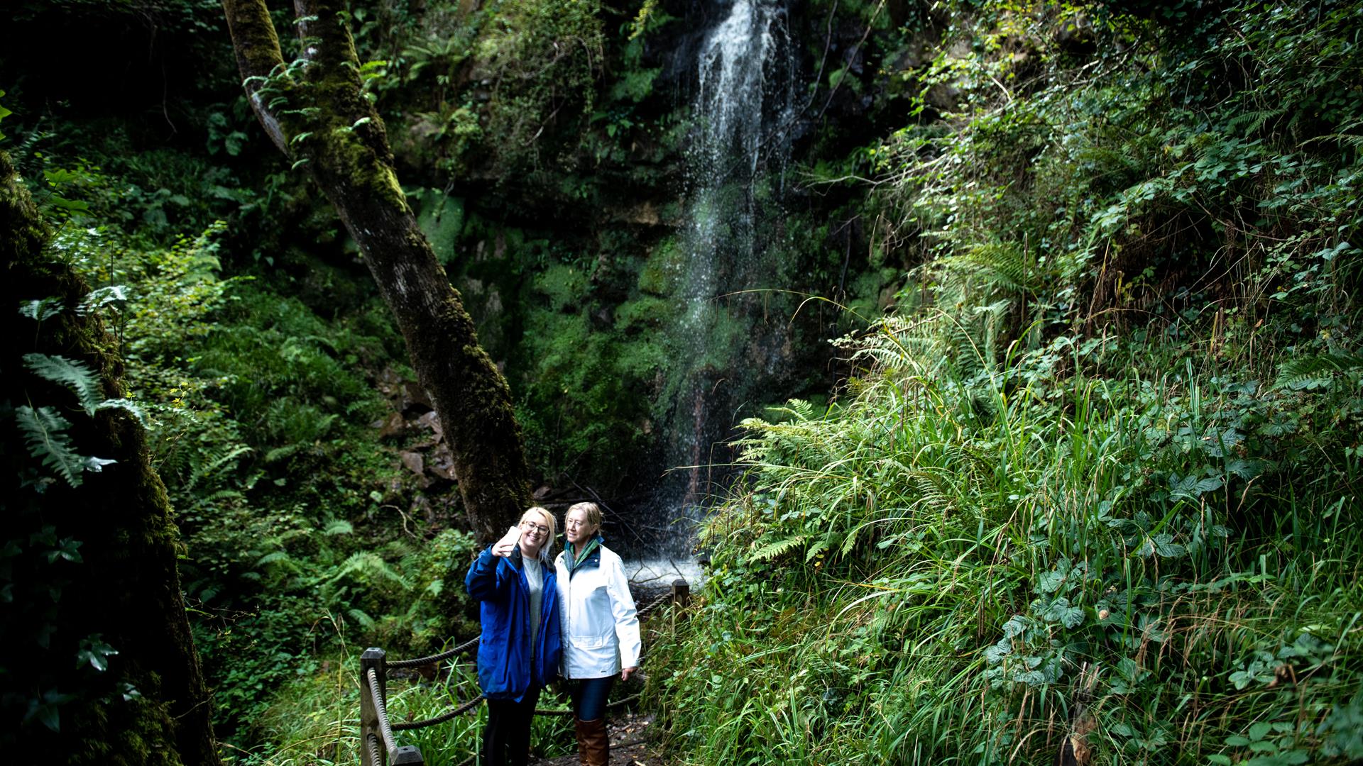 people getting photo with waterfall in background