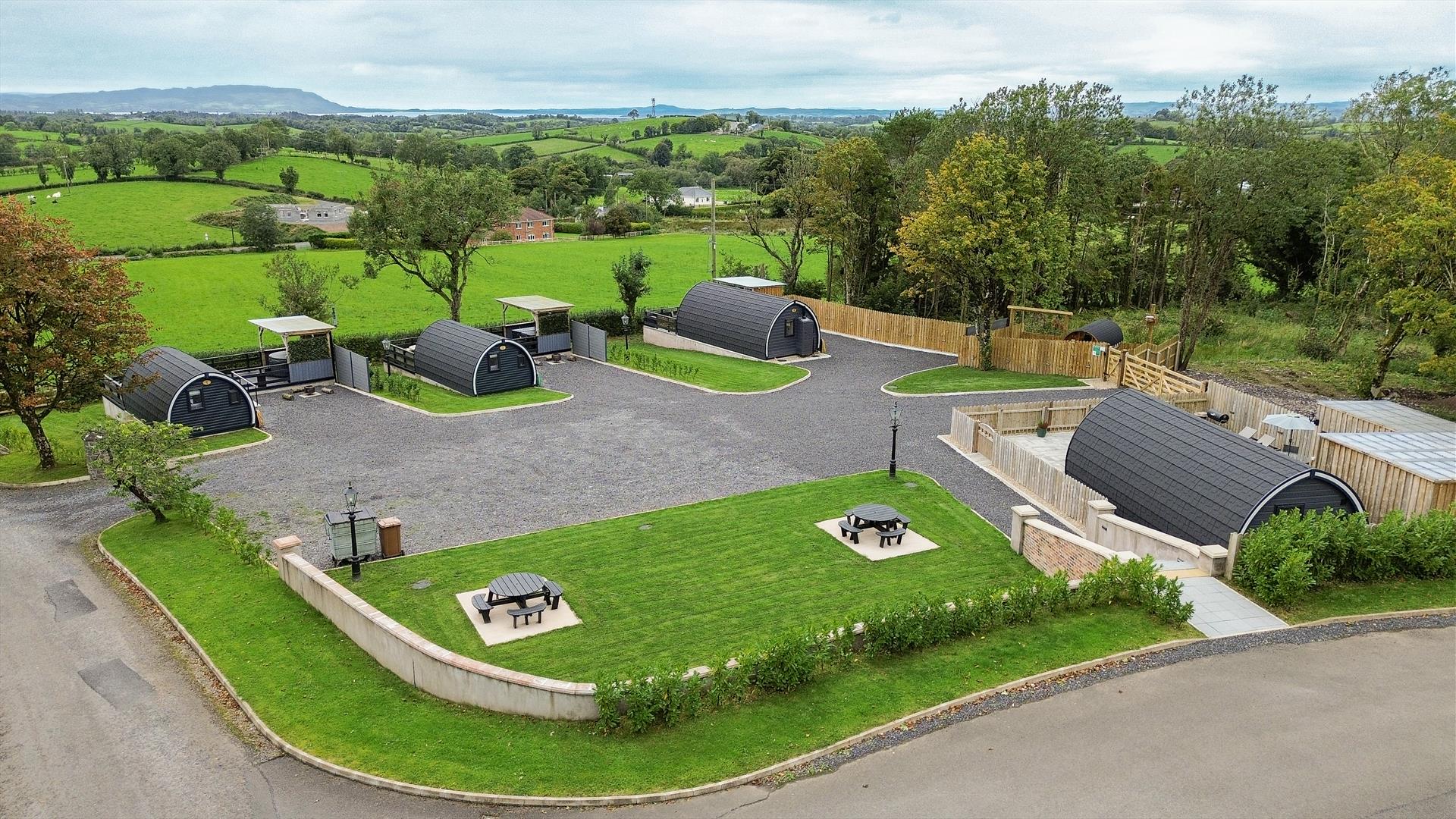Aerial view of Coolaness Glamping site with pod cabins, private outdoor areas, and surrounding countryside.