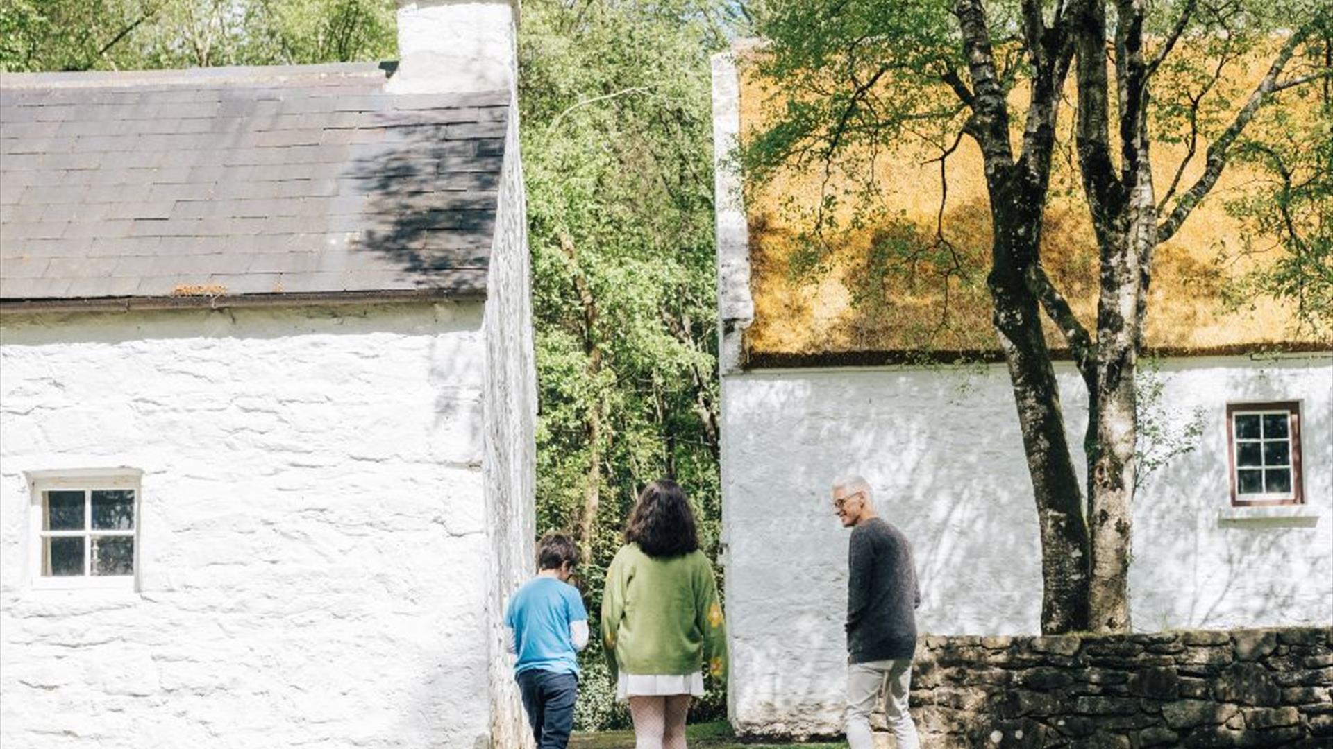 A family walking through the white cottages of the ulster american folk park