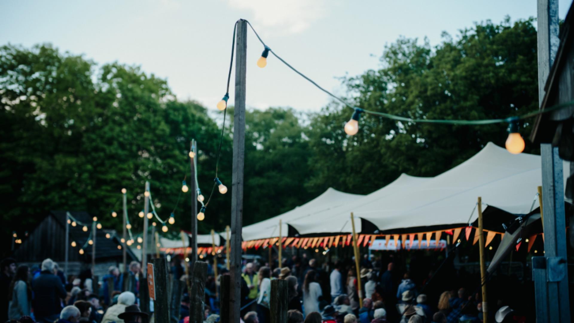 A white stretch tent, glowing lights and a distance crowd