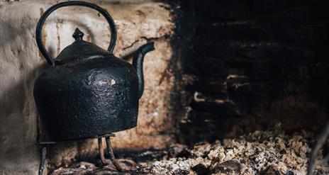 Image of a teapot on the hearth in a cottage at the Ulster American Folk Park