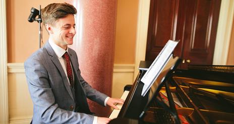 Pianist Jonathan Beatty sitting at a piano in Castle Coole