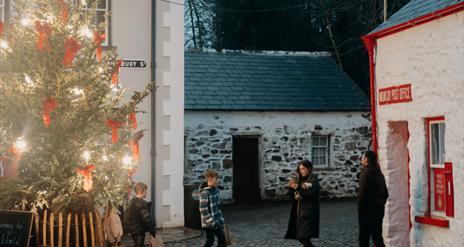 A family of four walking in the Folk Park at Christmas
