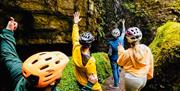 Visitors exploring the Marble Arch Caves in County Fermanagh, walking through a rocky cave passage surrounded by moss and natural formations.
