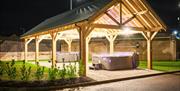 Night time image of hot tubs under canopy and lit up