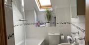 View of a bathroom with shower, bath, toilet and sink at Shamrock Cottage.