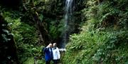 people getting photo with waterfall in background
