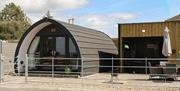 Exterior of glamping pod with private patio seating and covered hot tub area.