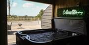 Hot tub overlooking an outdoor patio and countryside view.