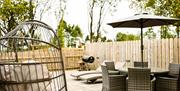 Outdoor patio with lounge chairs, fire pit, barbecue, and covered dining area enclosed by wooden fencing.