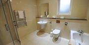 A spacious bathroom with a bath, sink, shower and toilet