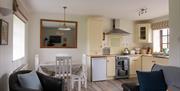 Kitchen and dining area with table and 4 chairs, cream kitchen cabinets, mirror, cooker and sink