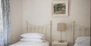 Simple white twin bedroom with lamp between beds