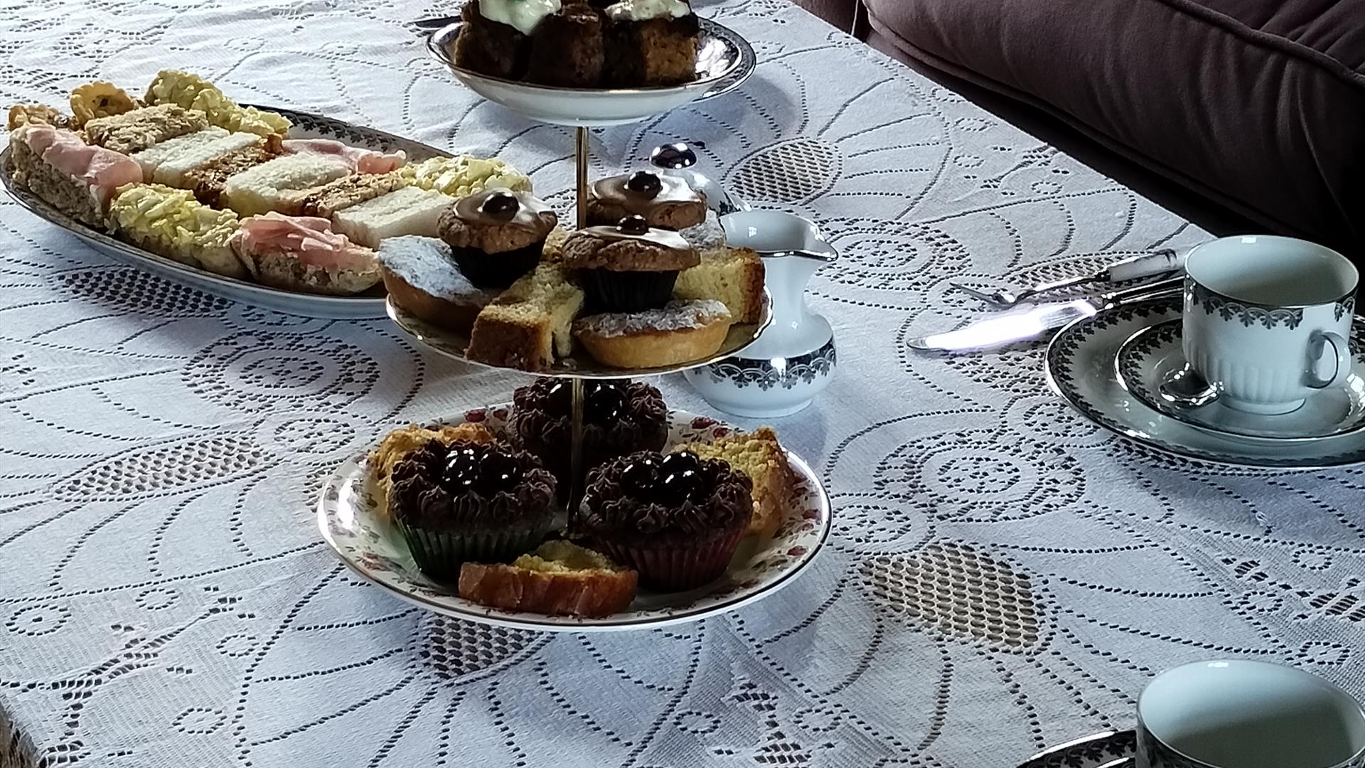 A table laid with plates of cakes and sandwiches