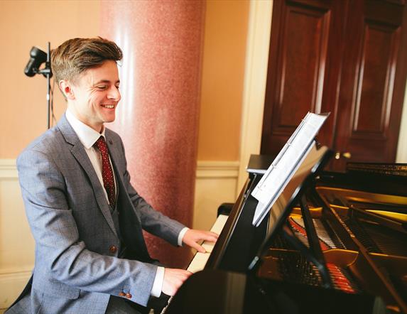 Pianist Jonathan Beatty sitting at a piano in Castle Coole